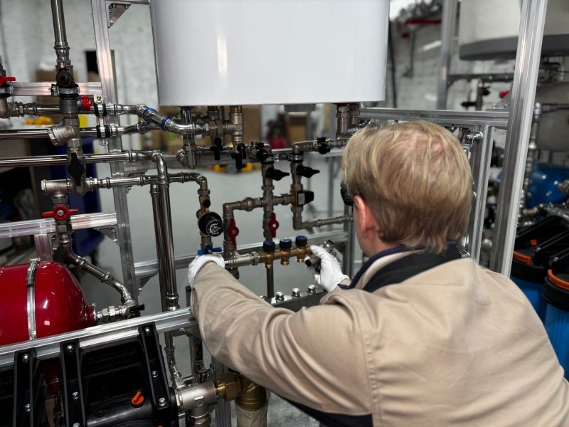 Heizungstechniker kalibriert einen modernen Heizungsverteiler in der Werkstatt