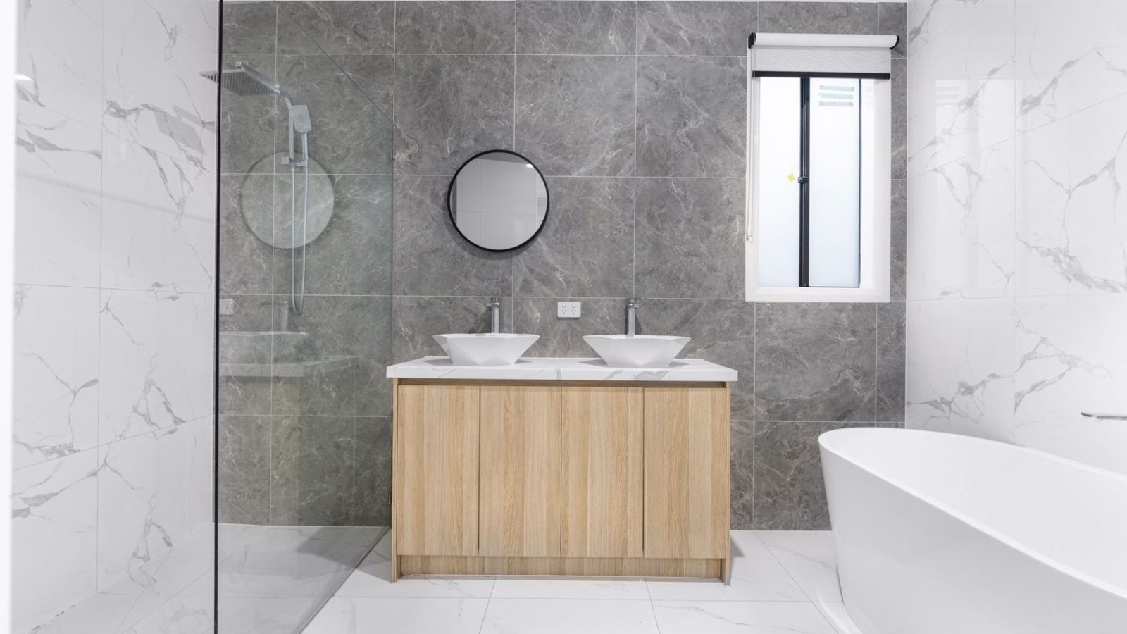 Modernes Badezimmer mit Doppelwaschtisch, Naturstein-Fliesen und freistehender Badewanne