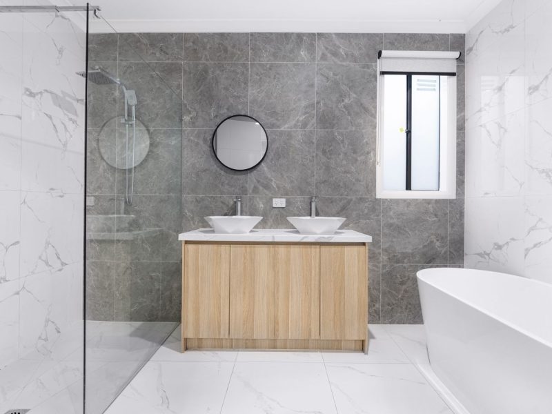 Modernes Badezimmer mit Doppelwaschtisch, Naturstein-Fliesen und freistehender Badewanne