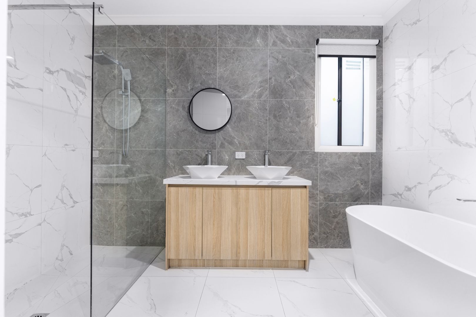 Modernes Badezimmer mit Doppelwaschtisch, Naturstein-Fliesen und freistehender Badewanne