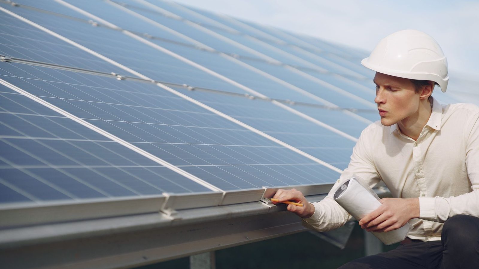 Techniker mit Schutzhelm prüft eine Solarthermie-Anlage auf dem Dach