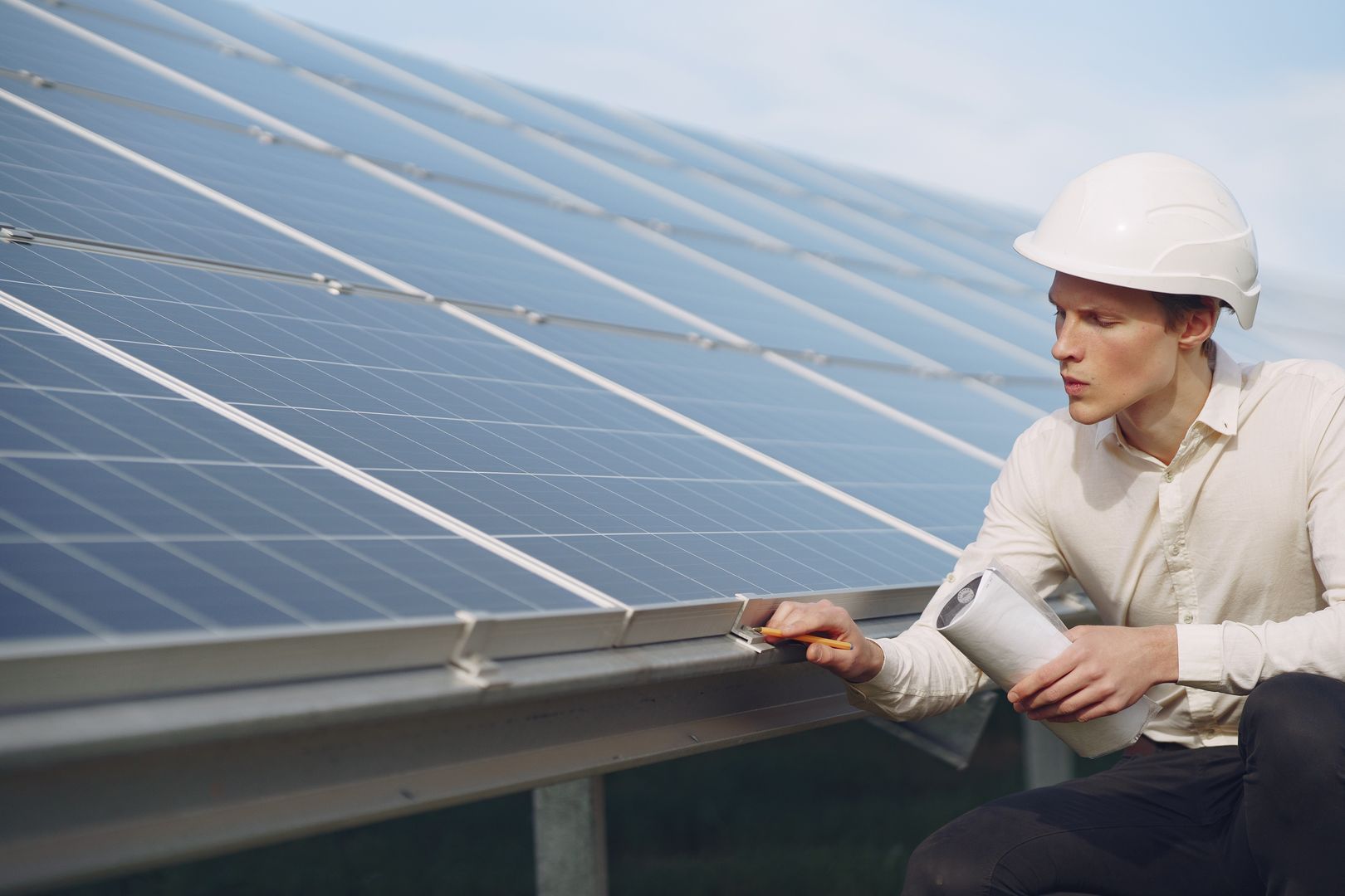 Techniker mit Schutzhelm prüft eine Solarthermie-Anlage auf dem Dach